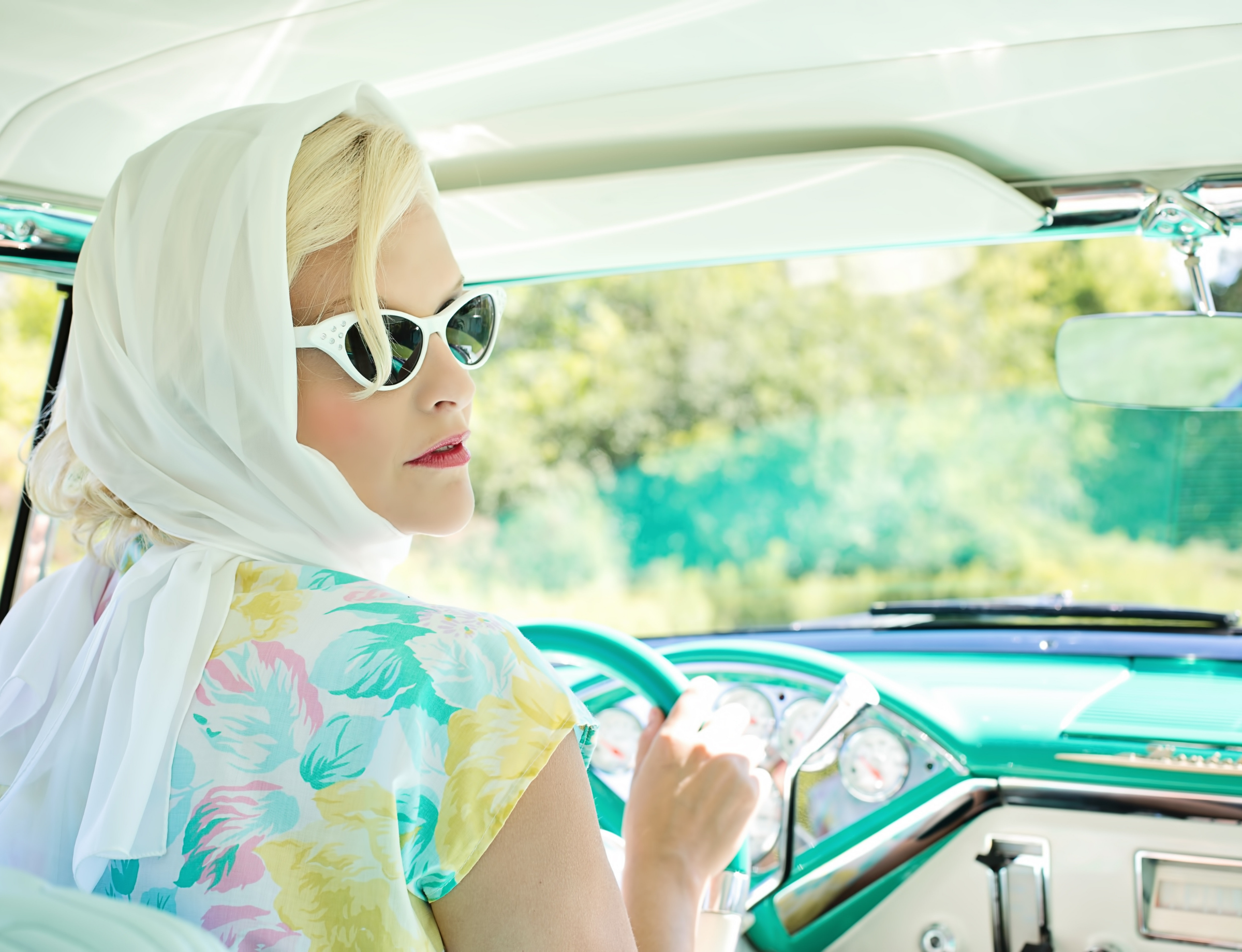 Woman driving in scarf and sunglasses