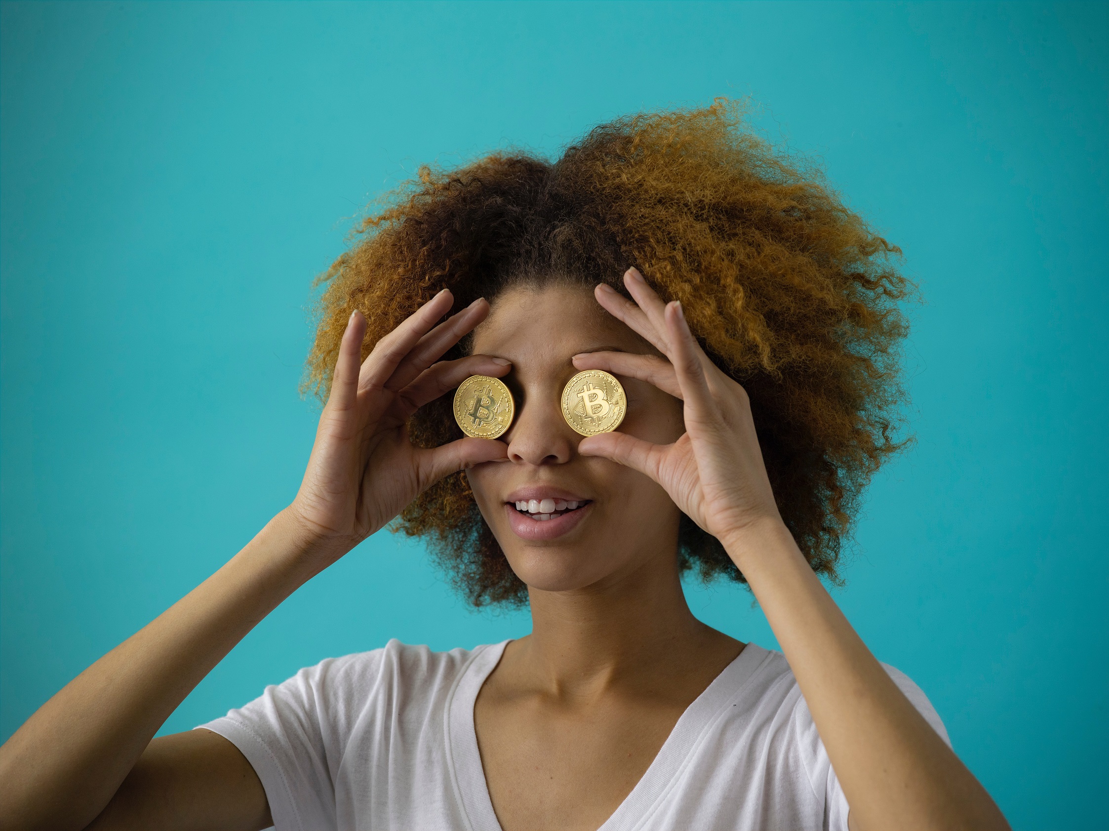 Black woman holding crypto currency to her eyes