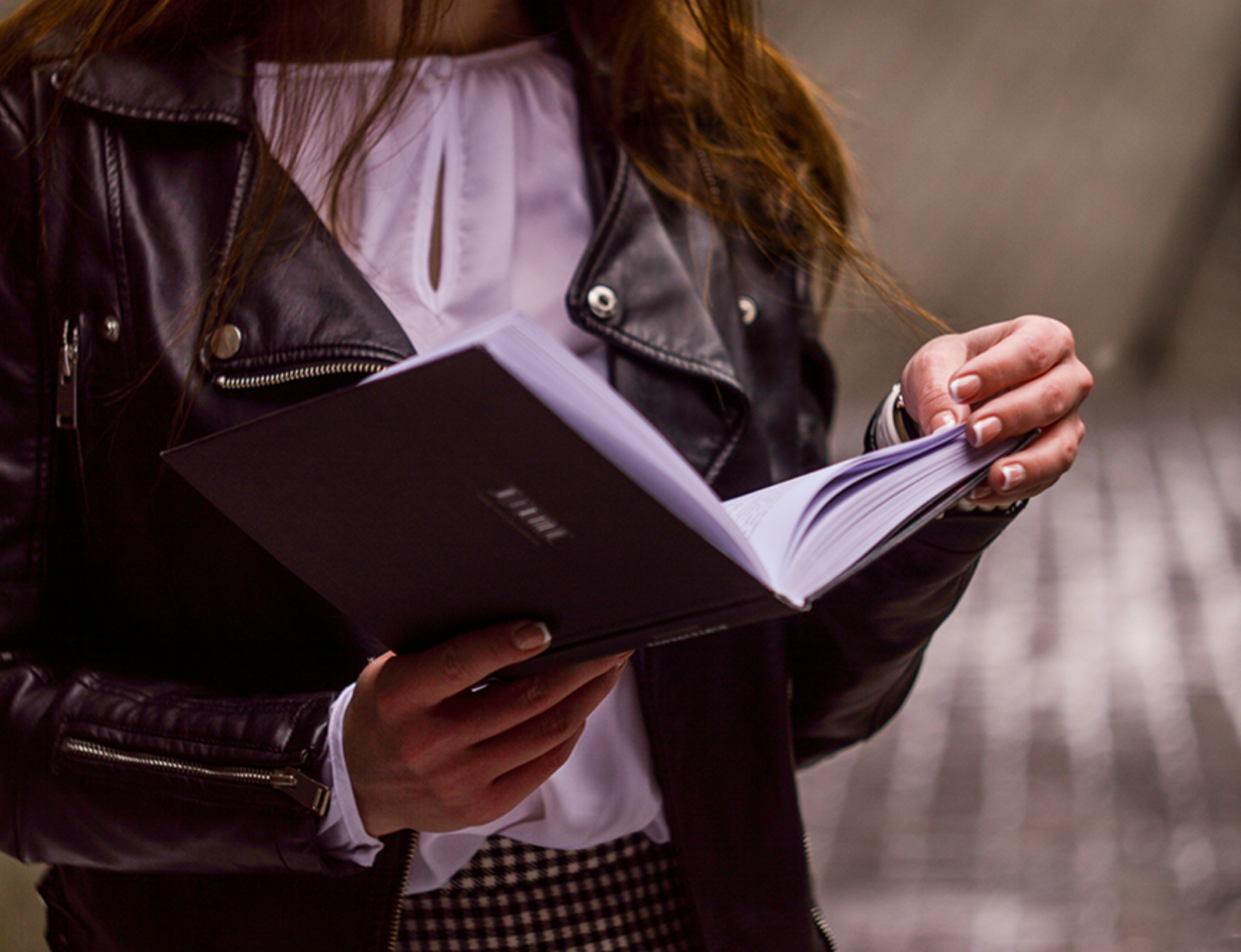 Girl in leather jacket holding a book